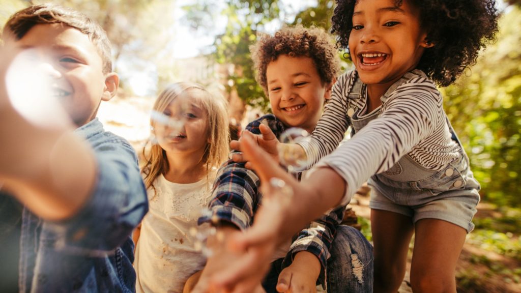 Enfants jouant et souriant dehors.